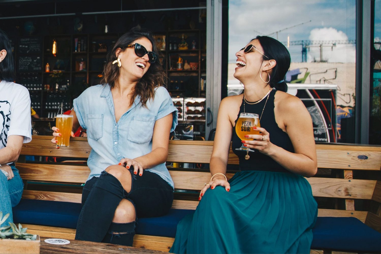 two females laughing while socializing and having a beer